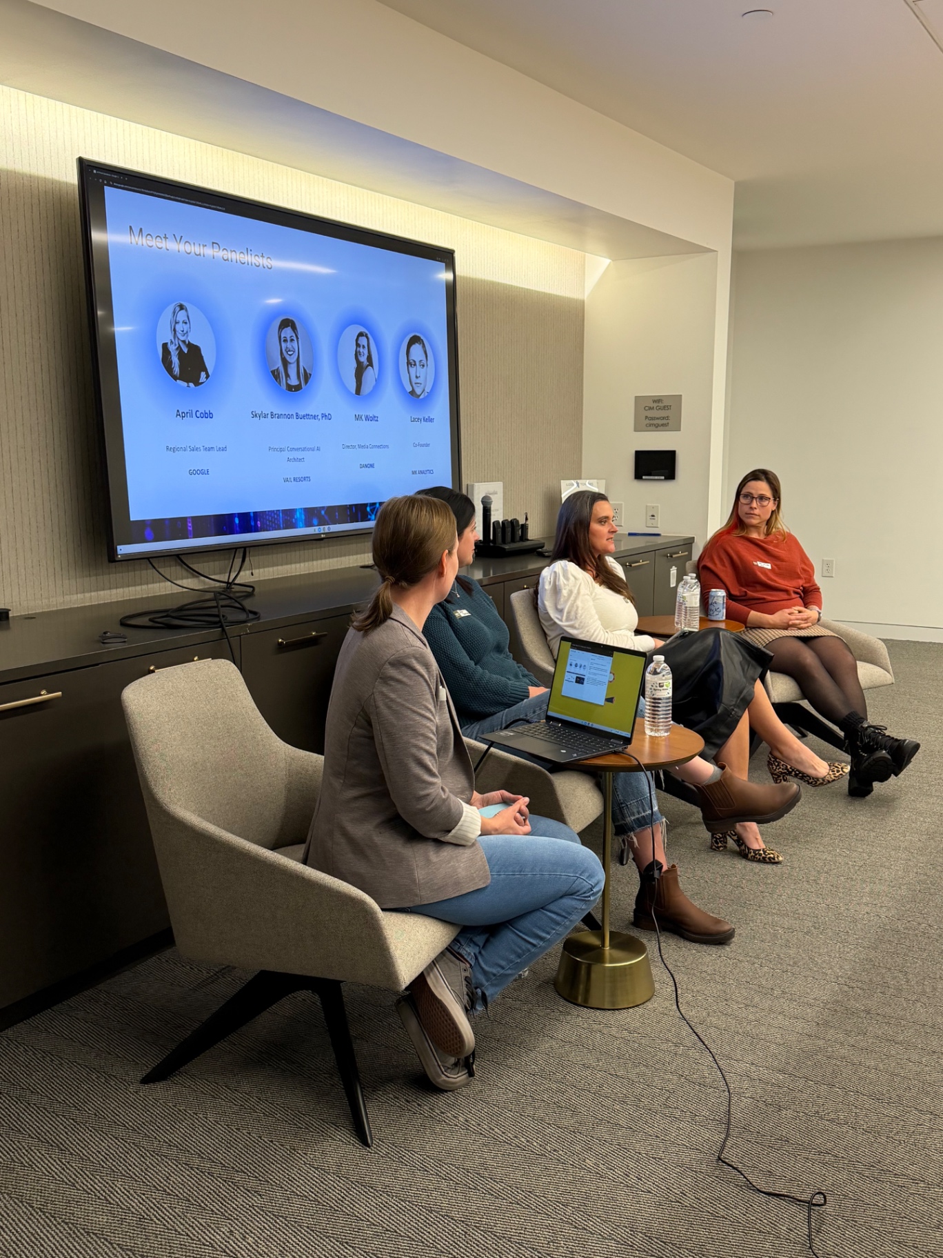 The Women in AI Denver panel seated in front of the panelist slide