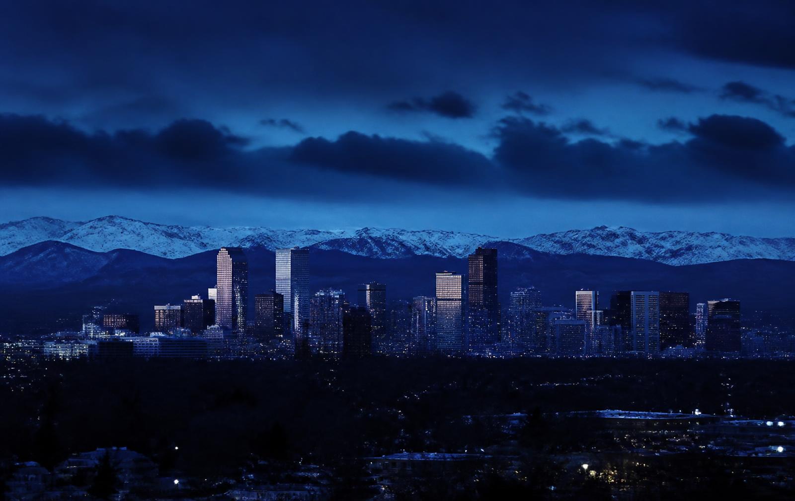 The Denver skyline at blue hour with the Rocky Mountains behind it
