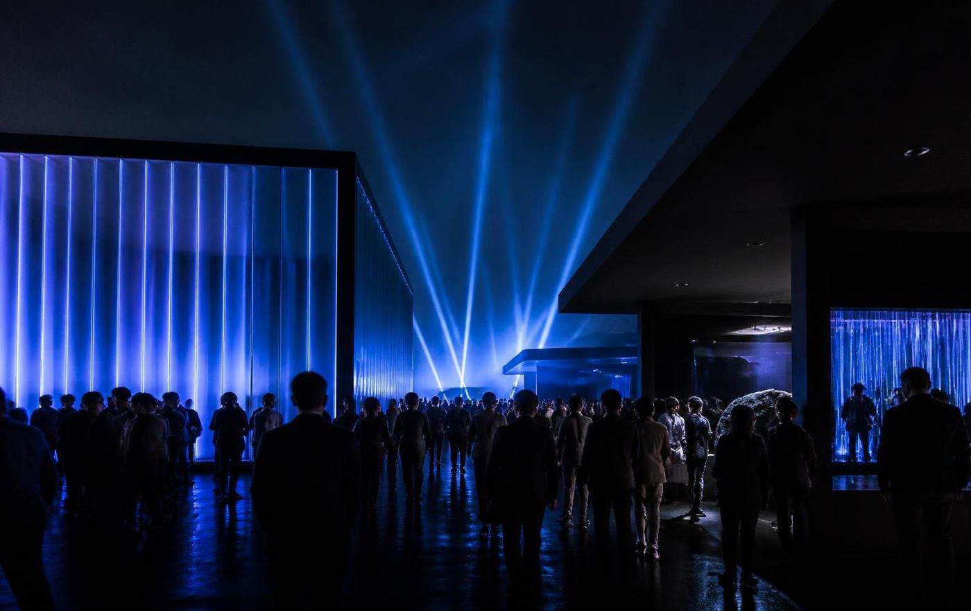 Guests moving through an immersive brand activation lit with blue light beams